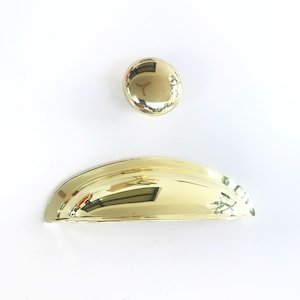 May include: Two gold cabinet knobs, one round and one shaped like a half-dome.