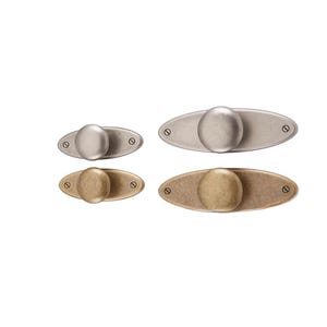 May include: Four oval cabinet knobs in varying metallic finishes: silver, brushed nickel, and antique brass. Each knob features a rounded, spherical handle attached to an oval backplate with two screw holes. The knobs are displayed against a white background.