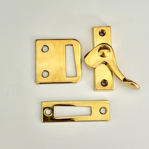 Könnte beinhalten: Ein Satz von drei goldfarbenen Fensterschloss aus Metall. Die Schlösser sind rechteckig mit einem Schlüsselloch und einem Hebelgriff.