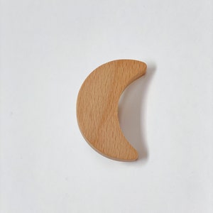 May include: A wooden crescent moon shape, made of light brown wood.