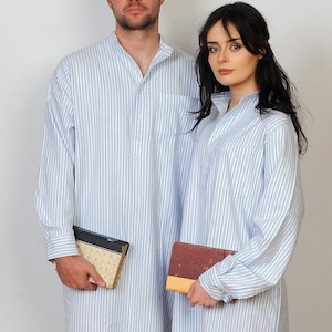 Op de afbeelding: Twee mensen dragen bijpassende langarmige shirts met blauwe en witte strepen. Ze houden boeken in hun handen.