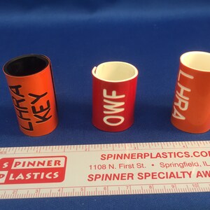 May include: Three red plastic award cylinders with white and black lettering. The cylinders are labeled "LHRA KEY", "OWF", and "LHRA".