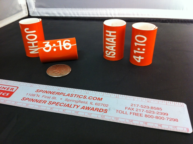 May include: Four orange plastic tubes with white text. The tubes have the following text: "JOHN 3:16", "ISAIAH", and "41:10".