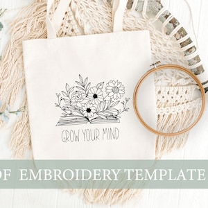 以下が含まれることがあります： 白いトートバッグに、開いた本から花が咲いている黒い線画が描かれています。本の下に「Grow Your Mind」という文字が印刷されています。