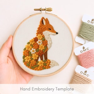 Op de afbeelding: Een borduurring met een gedetailleerd vossendesign. De vos is oranje, wit en bruin, met een lichaam gevuld met gele, oranje en witte bloemen. De tekst "Hand Embroidery Template" staat onderaan.