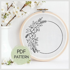 May include: A black and white embroidery pattern of a floral wreath with leaves and circles in a hoop. The text "PDF PATTERN" is on a green background.
