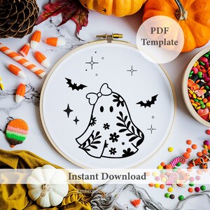 Op de afbeelding: Een borduurring met een Halloween-geestontwerp in zwart en wit, versierd met bloemmotieven, vleermuizen en sterren. De tekst "PDF Template" en "Instant Download" is zichtbaar. De afbeelding bevat pompoenen en snoep.