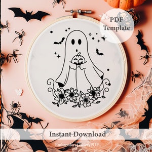 Peut inclure: Un motif de broderie en noir et blanc d'un fant&ocirc;me tenant une citrouille avec des fleurs en bas. Le motif est sur un cerceau de broderie blanc. Le texte "PDF Template" est dans le coin sup&eacute;rieur droit de l'image. Le texte "Instant Download" est en bas de l'image. Le texte "EmbroideryGalleryPDF" est en bas de l'image.