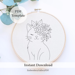 以下が含まれることがあります： 白い布に刺繍された、花の冠をかぶった猫の線画。木製のフレームに入っています。「PDF Template」と「Instant Download」の文字が見えます。ショップ名「EmbroideryGalleryPDF」も表示されています。