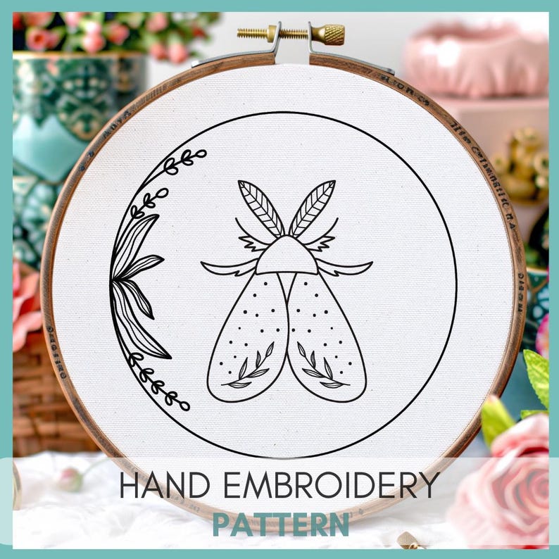 Peut inclure: Motif de broderie noir et blanc d'un papillon de nuit avec des d&eacute;tails floraux sur un tissu blanc dans un cerceau de broderie en bois. Le cerceau a un diam&egrave;tre de 15 cm. Le texte "HAND EMBROIDERY PATTERN" est imprim&eacute; sous le cerceau.