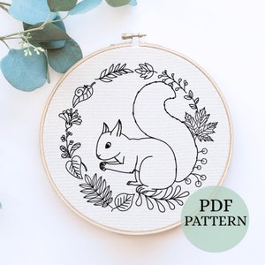 May include: Black and white line art embroidery pattern of a squirrel surrounded by leaves and flowers in a circular frame. The pattern is labeled "PDF PATTERN".