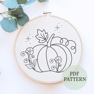 May include: A black and white line drawing of a pumpkin with a leaf and two flowers on a white background. The drawing is in a wooden embroidery hoop. The text "PDF PATTERN" is in the lower right corner of the image.