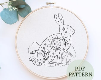 Könnte beinhalten: Schwarzweißes Linienkunst-Stickmuster eines Kaninchens mit einer Mondsichel, Sonne und Sternen. Das Kaninchen ist von Pilzen und Blättern umgeben. Das Muster ist mit "PDF PATTERN" beschriftet.