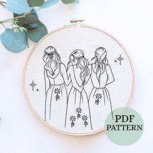 May include: Black and white line drawing of three women in dresses standing back to back with their arms around each other. The drawing is on a white background and is framed in a wooden hoop. The text "PDF PATTERN" is written in black below the hoop.