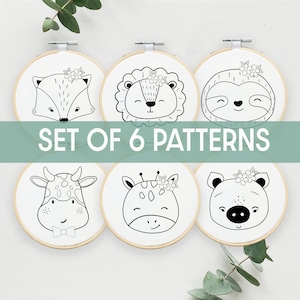 Op de afbeelding: Set van zes zwart-witte borduurpatronen met dierengezichten met bloemmotieven. De dieren zijn een vos, een leeuw, een luiaard, een koe, een giraffe en een varken.