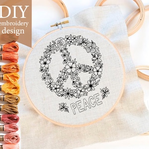 May include: DIY embroidery design featuring a peace sign surrounded by flowers with the word "PEACE" underneath. The design is on a white fabric stretched over a wooden embroidery hoop.