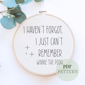 May include: A white embroidery hoop with the quote "I haven't forgot, I just can't remember. Winnie the Pooh" in black lettering. The hoop is on a white background.