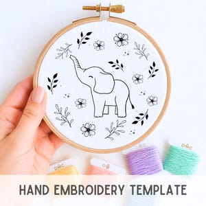 May include: A hand embroidery template featuring a line drawing of an elephant with its trunk raised, surrounded by floral and leaf designs. The design is set in a wooden embroidery hoop. The text "HAND EMBROIDERY TEMPLATE" is displayed at the bottom of the image.