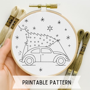 May include: A black and white embroidery hoop featuring a car carrying a Christmas tree, surrounded by stars. The text "PRINTABLE PATTERN" is at the bottom. Embroidery floss in shades of beige and green are in the background.