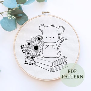 May include: Black and white embroidery pattern of a mouse sitting on a stack of books with flowers behind it. The pattern is on a white fabric background in a round embroidery hoop. The text "PDF PATTERN" is on a green background below the hoop.