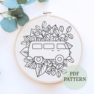 May include: Black and white line art embroidery pattern of a vintage van with floral details. The pattern is displayed on a white background in a wooden embroidery hoop. The text "PDF PATTERN" is written in green on a white circle.