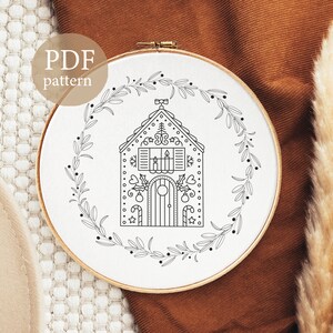 K&ouml;nnte beinhalten: Schwarz-wei&szlig;-Linienzeichnung einer Lebkuchenhaus mit einem Kranz darum. Der Text "PDF pattern" befindet sich oben im Bild.