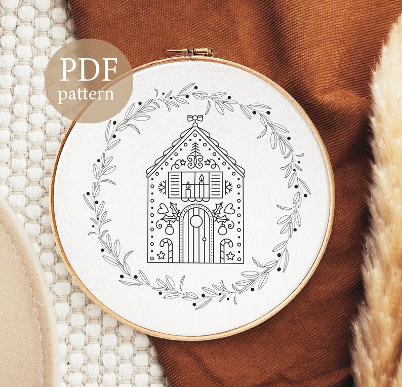 K&ouml;nnte beinhalten: Schwarz-wei&szlig;-Linienzeichnung einer Lebkuchenhaus mit einem Kranz darum. Der Text "PDF pattern" befindet sich oben im Bild.