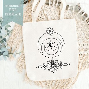 May include: A white tote bag featuring a black embroidered design of a sun, moon, and flower. The embroidery design is minimalist in style. The text "EMBROIDERY PDF TEMPLATE" is on a blue background.