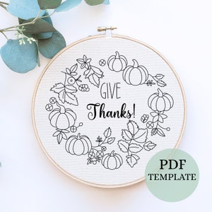 May include: Black and white embroidery pattern featuring a wreath of pumpkins, leaves, and berries with the text "Give Thanks!" in a cursive font.  PDF template.