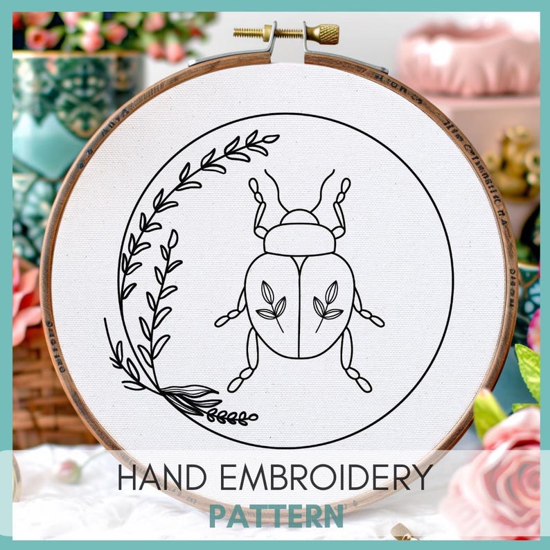 Peut inclure: Un dessin au trait noir et blanc d'un scarab&eacute;e avec une branche feuillue sur un cercle de broderie blanc. Le cercle est en bois et a une finition brune. Le texte "HAND EMBROIDERY PATTERN" est imprim&eacute; sous le cercle.