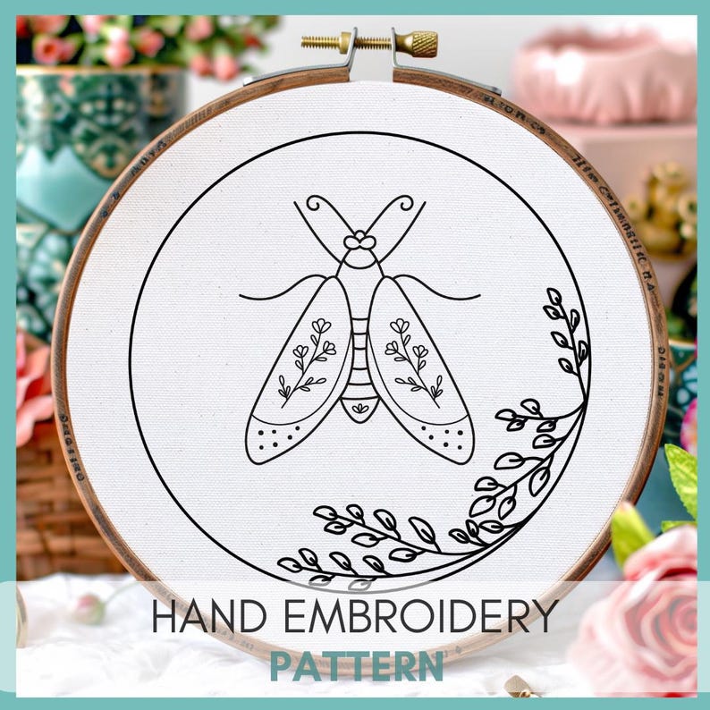 Peut inclure: Un motif de broderie &agrave; la main en noir et blanc d'un papillon de nuit avec des d&eacute;tails floraux sur un tissu blanc dans un cerceau de broderie en bois. Le cerceau a un anneau en bois brun avec une pince m&eacute;tallique et des marques en pouces. Le texte "HAND EMBROIDERY PATTERN" est imprim&eacute; sous le cerceau.