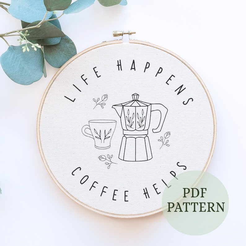 May include: A white embroidery hoop with the text "Life Happens Coffee Helps" and a black line drawing of a coffee pot and a cup of coffee.