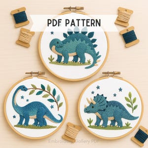 May include: Three dinosaur embroidery hoop art pieces. Each features a different dinosaur in shades of blue and green, set against a white background. The text "PDF PATTERN" is displayed. Embroidery floss spools are scattered around the hoops.