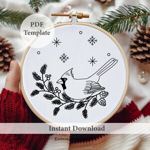 K&ouml;nnte beinhalten: Schwarzwei&szlig;es Stickmuster eines Kardinals, der auf einem Zweig mit Beeren und Tannenzapfen sitzt. Das Muster befindet sich in einem runden Stickrahmen mit dem Text "PDF Template" und "Instant Download" auf dem Bild.