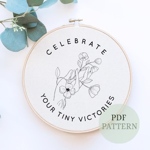 Puede incluir: Patrón de bordado en blanco y negro en un aro de tela blanco con el texto "Celebra tus pequeñas victorias" y "Patrón PDF".