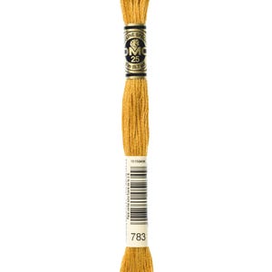 May include: A spool of DMC embroidery floss in colour 783, a golden yellow. The spool is labelled with the DMC logo and the number 25, indicating the length of the floss. The label also includes the text "Para venta solo fuera de la U.E" and a barcode.
