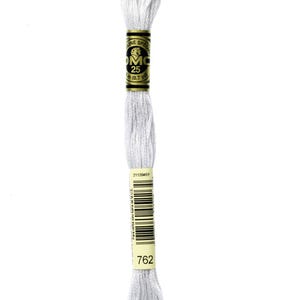 Könnte beinhalten: Ein Knäuel DMC Stickgarn in Farbe 762, ein helles Grau. Das Garn ist um ein gelbes und goldenes Etikett mit dem DMC-Logo und dem Text "DMC Special Mouliné 25m (8.7 yds)" gewickelt. Das Etikett enthält auch einen Barcode und die Nummer 2112045Y.
