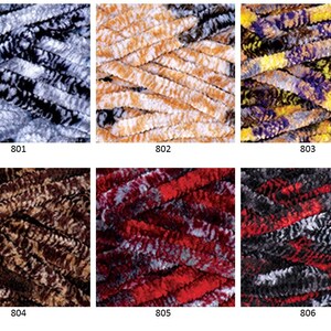 K&ouml;nnte beinhalten: Sechs Kn&auml;uel Garn in verschiedenen Farbkombinationen. Das Garn hat eine flauschige, chenilleartige Textur. Die Farben sind: 801 - Schwarz und Wei&szlig;, 802 - Braun und Wei&szlig;, 803 - Lila, Gelb und Schwarz, 804 - Braun und Wei&szlig;, 805 - Rot und Wei&szlig;, und 806 - Schwarz, Rot und Wei&szlig;.