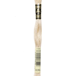 May include: A skein of DMC embroidery floss in the color ecru. The floss is wound around a cardboard spool with a gold label that reads "DMC" and "25". The label also includes the text "Genuine Special" and "Para venta solo fuera de la U.E."