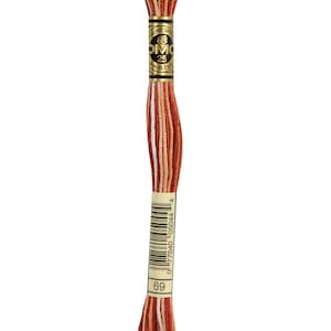 May include: A skein of DMC embroidery floss in color 69, a blend of red, orange, and white. The floss is wrapped around a white card with a black and gold label that reads "DMC 25" and a barcode.