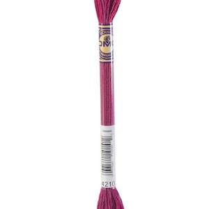 May include: A single skein of DMC embroidery floss in a vibrant shade of magenta. The floss is tightly wound and packaged with a paper label that includes the color number 4210 and a barcode. The thread is approximately 8 meters long.