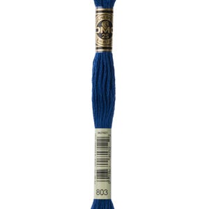 Puede incluir: Una bobina de hilo de bordar DMC en color 803, un azul oscuro. El hilo está enrollado alrededor de una tarjeta blanca con una etiqueta dorada que dice "DMC" y "25" en un círculo negro. La etiqueta también incluye un código de barras y el texto "8 m (8,7 yd)".
