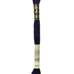 May include: A spool of DMC embroidery floss in color 823, a deep navy blue. The floss is wound around a white card with the DMC logo and the number 823 printed on it.