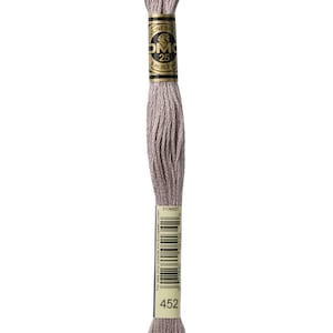 May include: A skein of DMC embroidery floss in color 452, a light gray shade. The floss is wound around a cardboard spool with a gold label that reads "DMC" and "25 m (82 yd)".