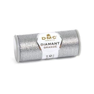 Puede incluir: Carrete de hilo DMC Diamant Grandé plateado. La etiqueta dice "DIAMANT GRANDÉ" y "G415 - silver". El hilo es de color plateado metálico, enrollado alrededor de una bobina gris con tapas blancas. Ideal para bordados y costuras decorativas.