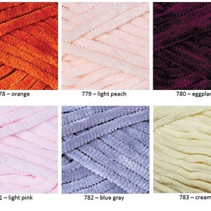 K&ouml;nnte beinhalten: Sechs Kn&auml;uel Garn in verschiedenen Farben, darunter Orange, Hellpfirsich, Aubergine, Hellrosa, Blaugrau und Creme. Das Garn hat eine weiche, flauschige Textur.