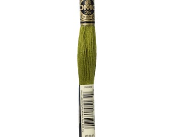 May include: A spool of DMC embroidery floss in color 580, a dark green shade. The spool is labeled with the DMC logo and the number 25, indicating the length of the floss. The label also includes the text "Mouline Special" and "8 m (8.7 yd)".