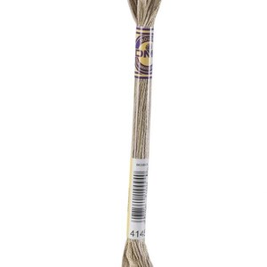 May include: A single skein of DMC embroidery floss in a neutral, light brown color. The floss is wrapped around a cardboard tube with a yellow and purple label. The label includes the DMC logo, a barcode, and the number 4145.
