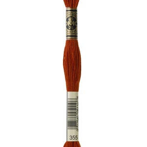 Peut inclure: Une bobine de fil à broder DMC de couleur orange brûlé, portant le numéro 355. L'étiquette affiche le logo DMC et des informations sur le produit. Le fil est bien enroulé et prêt à l'emploi.