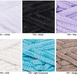 K&ouml;nnte beinhalten: Sechs Kn&auml;uel Garn in verschiedenen Farben: Wei&szlig;, Schwarz, Lila, Milch, Hellt&uuml;rkis und Beige. Das Garn hat eine flauschige, chenilleartige Textur.